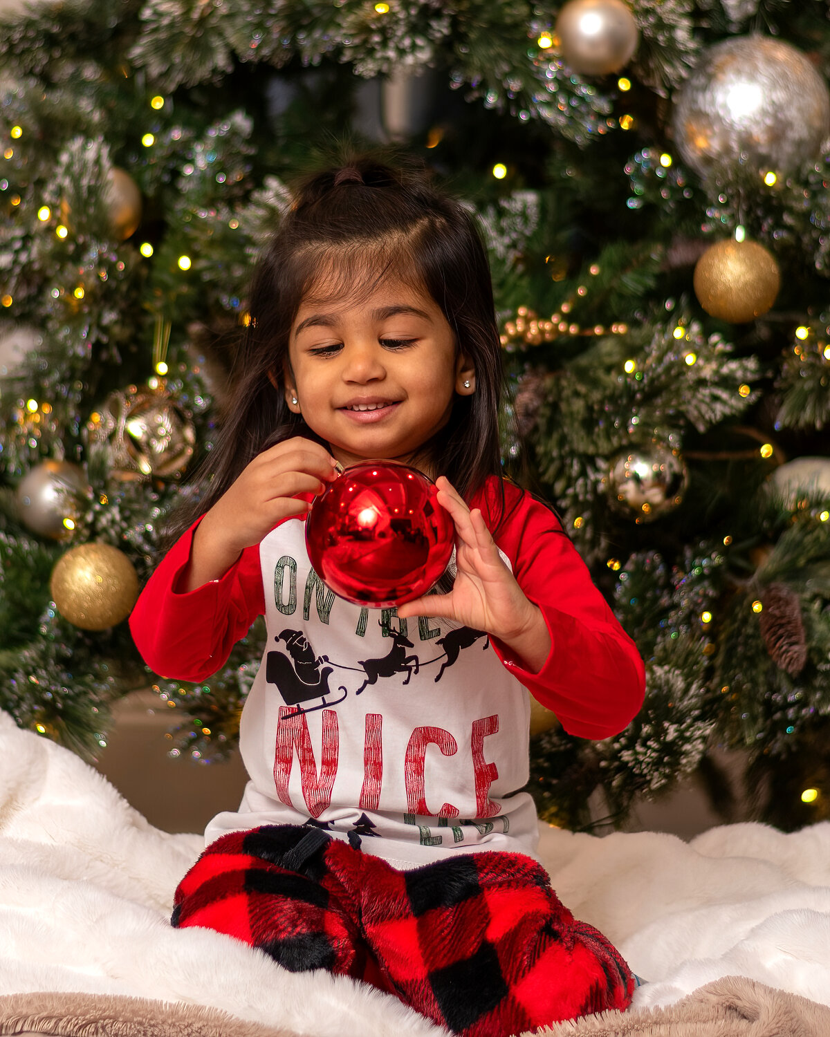 Holiday portrait — girl with ornament, Christmas tree